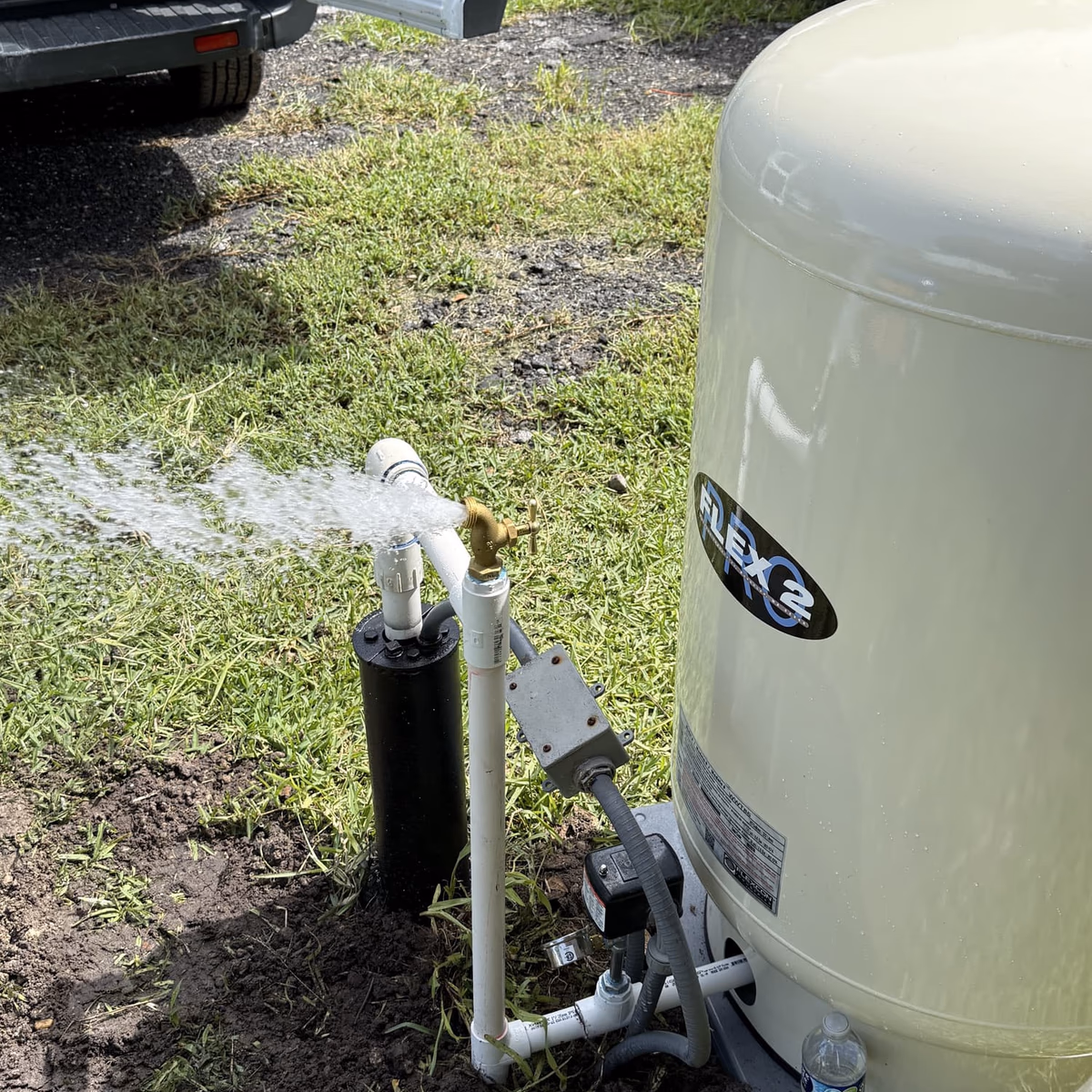 water flowing from a well system next to a pressure tank